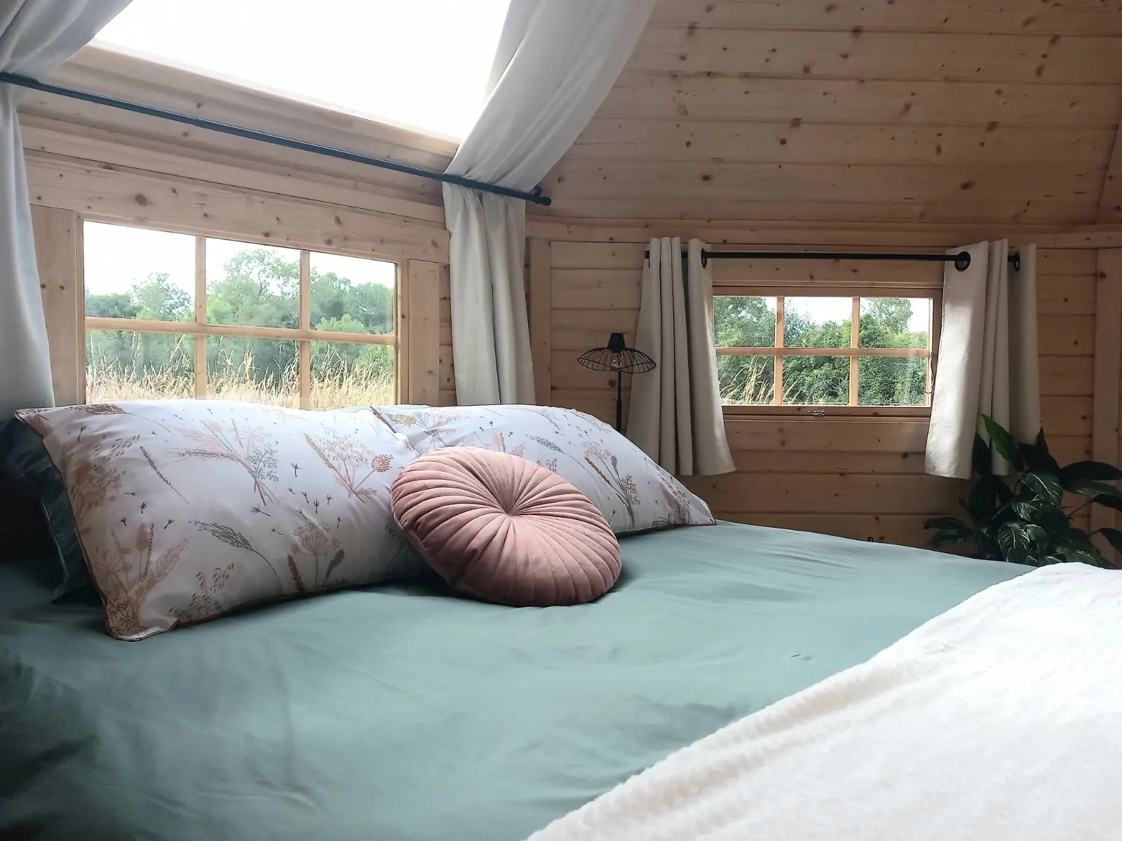 Jardin arboré avec brasero et chaises en bois devant un gîte moderne