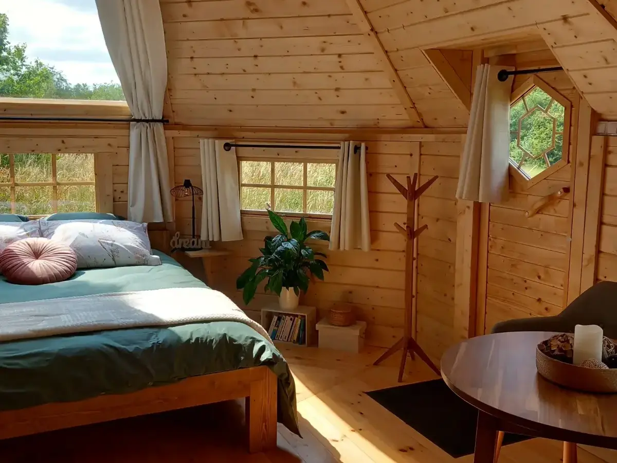 Jacuzzi extérieur en bois sur terrasse avec pergola, dans un jardin verdoyant