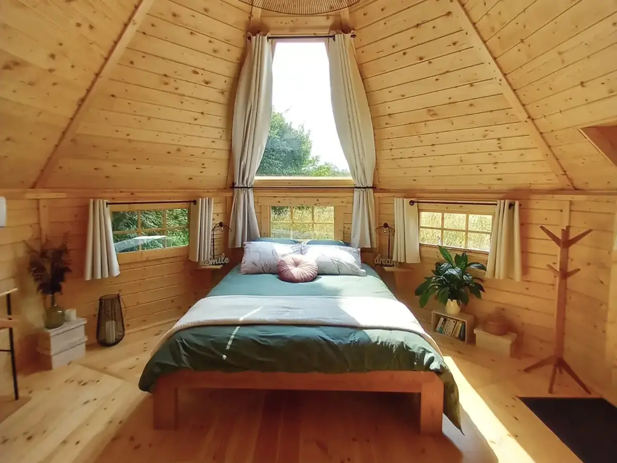 Un kota finlandais au milieu d'un champ verdoyant, entourée de nature et de tranquillité.
